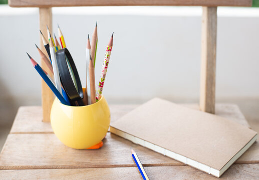 Colorful group of pencil with notebook on wood table.