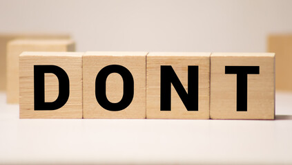 Hand flipping one wooden cube to change the word Don't for Do it on neutral background
