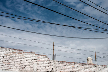 Paisaje Urbano con cables, estructura urbana,  pared con ladrillos, cielo azul, energía