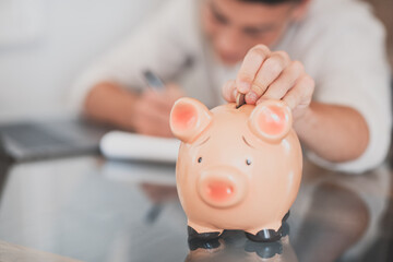 Man sit at desk manage expenses, calculate expenditures, pay bills online use laptop, makes household finances analysis, close up focus on pink piggy bank. Save money for future, be provident concept.