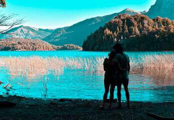 pareja abrazada mirando hacia el horizonte en el lago y las montañas