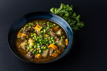 beef stew with potato and vegetables in a plate on a dark table