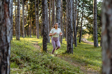 Side view full length of young caucasian woman running trough the woods in nature outdoor jogging in sunny day - sport fitness and recreation concept real people copy space