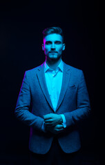 Young handsome model posing in a studio in a trendy neon light. Fashionable man in a stylish suit....