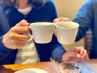 コーヒーカップで乾杯する2人の手