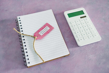 women-owned business tag with calculator and notepad on pink desk, supporting equality