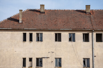 Facade of a residential building, abandoned, in decay, with plenty of windows with broken glass,...