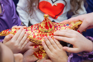 Golden Red Old magic lamp . They touch the old magic lamp with their hands .