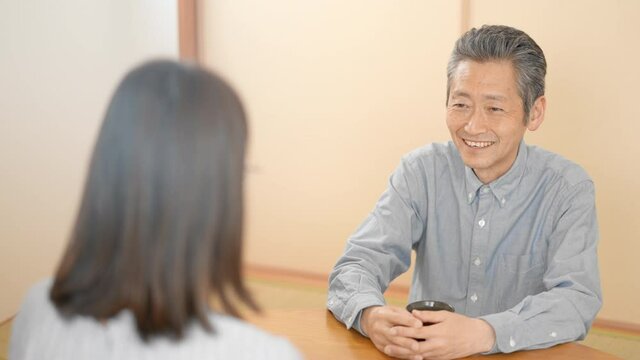 和室で会話をする若い女性とシニア男性