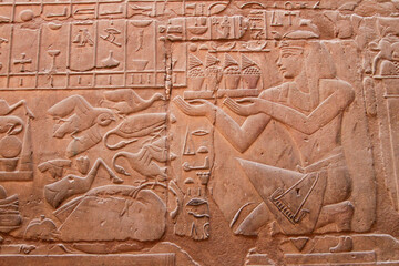 Carved sandstone relief of pharaoh and hieroglyphics on wall at Karnak Temple, Luxor, Egypt 