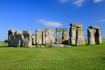 Stonehenge in the late afternoon with blue sky and green grass 