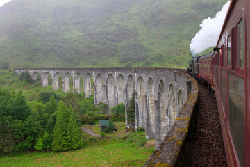Steam train going over Glenfinnan Viaduct in rural Scotland