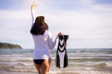 Sporty asian woman holding flippers in the sea,Summer holidays travel concept © gballgiggs