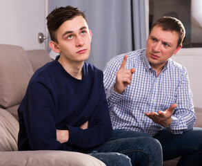 Adult man is asking forgiveness from his sad son after conflict at the home.