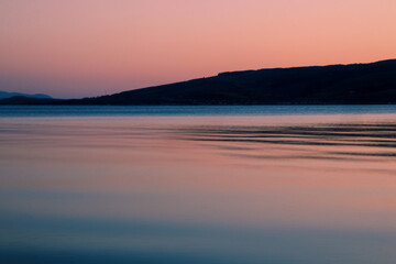 Obraz premium Smooth water at sunset, land silhouettes of an island in Gourock 