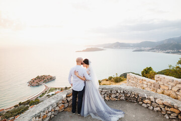 Fototapeta na wymiar The bride and groom are embracing on the observation deck overlooking the island of Sveti Stefan 