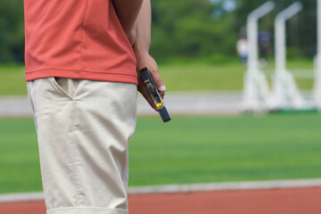 陸上競技場でスターターピストルを持つ男性の手