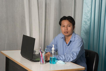 Obraz na płótnie Canvas Scared or nervous! Portrait of emotional nervous young businessman in blue shirt are sitting in room working online window background