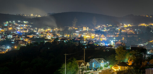 Fototapeta na wymiar Night scene in the valley bright houses with colorful lights makes the night scene in the countryside more vibrant in the Da Lat plateau, Vietnam