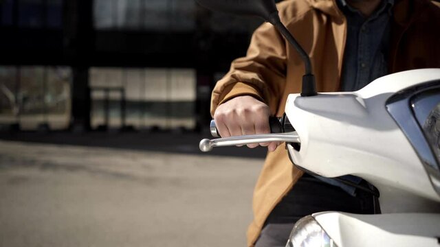 Close-up of the motorcyclist's hand. The concept of speed, movement, forward motion, acceleration, transportation in the city. A male hand turns the throttle of an urban motorcycle.