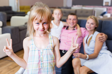 Young girl is happyning of new sofa in furniture store.