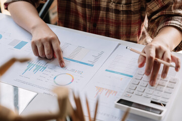 Close up hand of woman using calculator for do math finance on wooden desk in office and business working background, tax, accounting, statistics and analytic research concept.