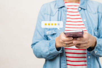 Customer experience ratings concept. A stylish woman using a smartphone to submit stars feedback, and review to products or services she quite satisfied. Marketing business important tools. Surveys.