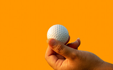 Golfer showing golf ball on hand holding with orange color background.