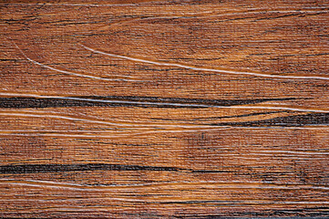 A flat surface of polished old brown wood with black longitudinal stripes.