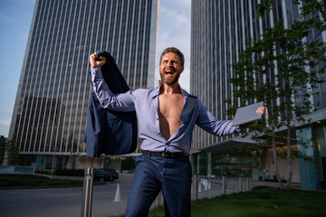 Fototapeta premium Excited businessman model in unbuttoned shirt outdoor office city. Ambitions concept and success business.