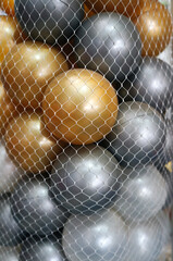 Textures, patterns and backgrounds of gold and white plastic balls are in a mesh bag.