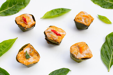 Thai streamed fish curry in banana leaves with noni or morinda citrifolia leaves on white