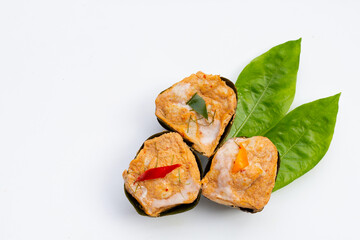 Thai streamed fish curry in banana leaves on noni or morinda citrifolia leaves on white background.