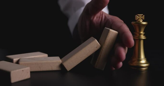 4K Video slow motion close up hand stop domino effect to make king chess fall . business concept of try to stop the domino effect