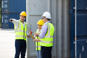 Group of professional dock worker and engineering people wearing hardhat safety helmet and vest working at container yard port of import export. Business teamwork concept