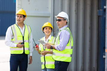 Group of professional dock worker and engineering people wearing hardhat safety helmet and vest working at container yard port of import export. Business teamwork concept