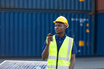 worker talking on walkie-talkie to Colleague at container warehouse at port of import and export goods. African American Industrial factory and energy engineering Specialist.