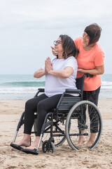 Mature woman in a wheelchair being helped with her meditation pose: Health and inclusivity concept.