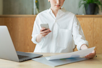 リモートワーク中にスマートフォンを確認する女性