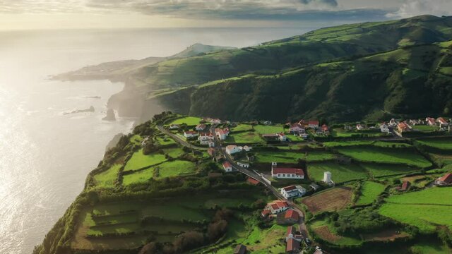 Overhead shot of village of Casa do Gato Tomas located on cliffs of Flores Island in atlantic ocean, Azores, Portugal, Europe. Aerial view of houses surrounded green mountains, 4k footage