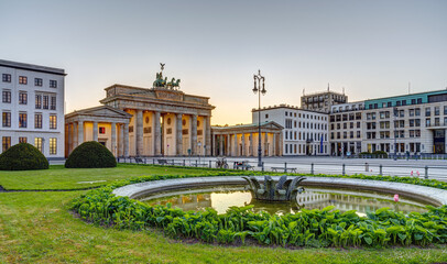 The famous Brandenburg Gate in Berlin after sunset with a fountain