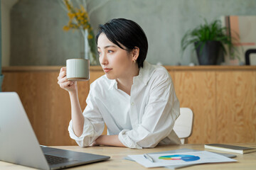 コーヒーを飲みながらリモートワークをする女性