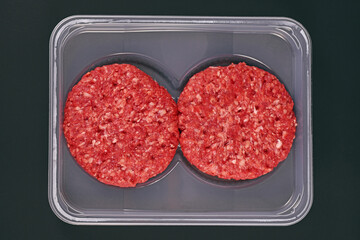 Raw round burger patties in package on dark background