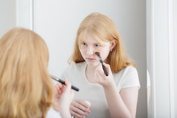 teen girl examines acne in front of mirror