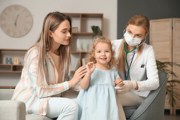 Obraz premium Pediatrician examining little girl at home