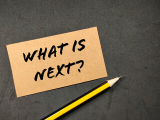 Business concept.Word WHAT IS NEXT with pencil on black background.