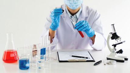 Young Asian scientist Working looking through a microscope doing research for analyzing a Experiments sample in a forensic laboratory.