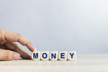 A word "Money" on a wooden table over the light background. 