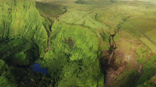  Overhead shot of mountains covered green grass in Poco Ribeira do Ferreiro, Alagoinha, Flores Island, Azores, Portugal, Europe. Amazing view of valley with waterfall and lake, 4k footage