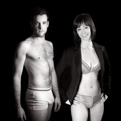 Beautiful couple wearing underwear in front of dark studio background, black and white photo